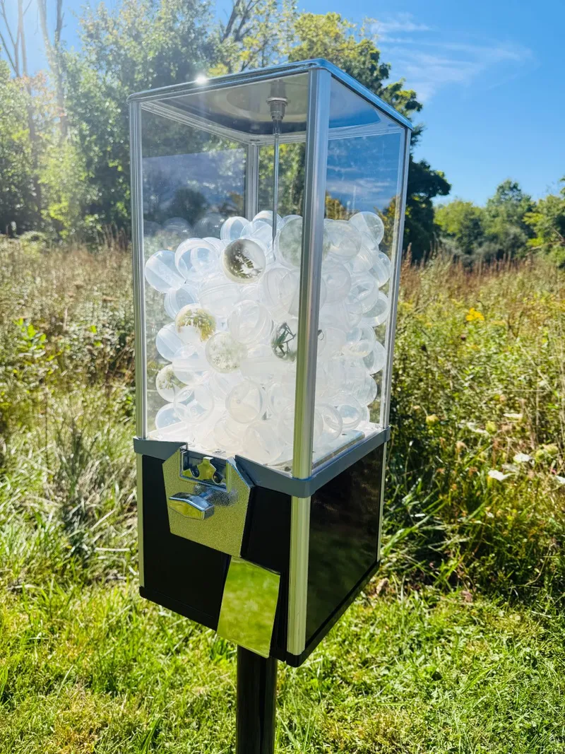 Close view of the machine's case packed with clear capsules, each holding a pressed wildflower